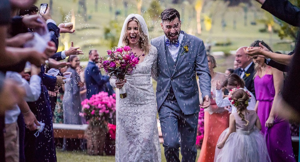 Casal entrando em cerimônia ao ar livre, chuva de arroz.