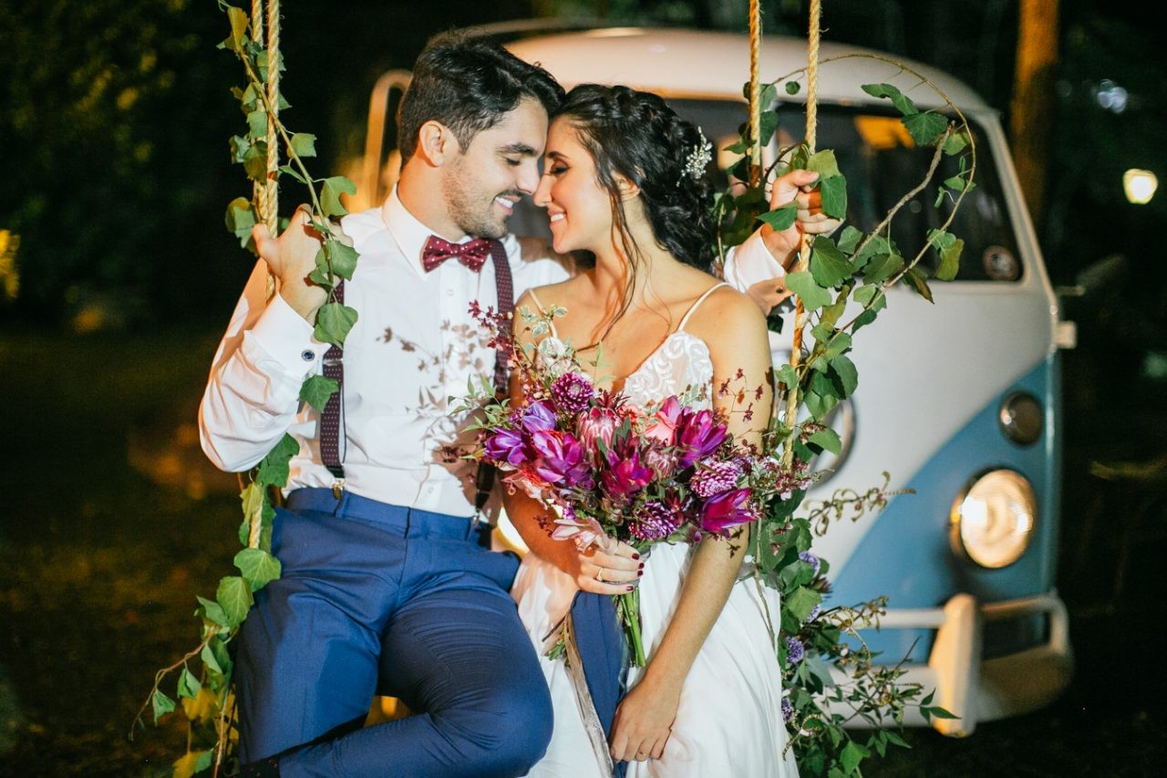 casal de noivos posando em frente a uma kombi em um casamento rústico ao ar livre