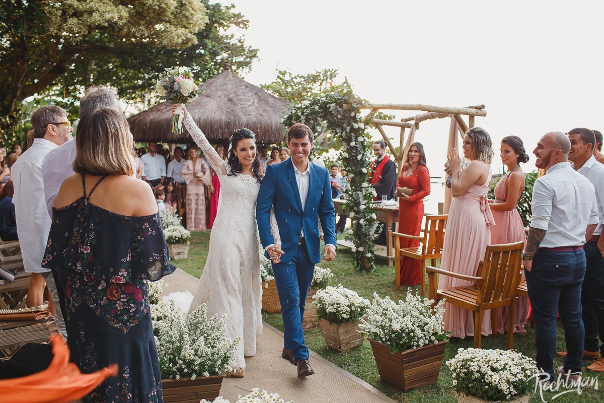 Noivos saindo da cerimônia em casamento rústico na praia