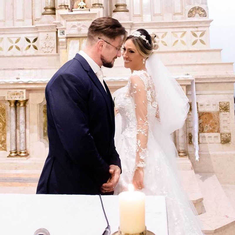 Paulo Muzy e Roberta Carbonari posam para foto após cerimônia religiosa.